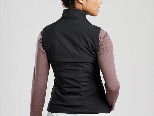 A back view of a woman wearing the ewool PRO+ Heated Vest in black over a long-sleeve top