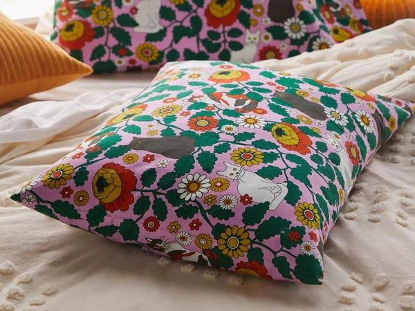 pink pillowcase with prints of daisies and white and black cats