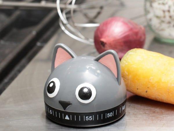 a plastic gray cat head with pink ears and a kitchen timer dial attached at bottom
