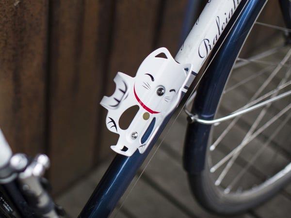 a white and black lucky cat water bottle holder attached to bike