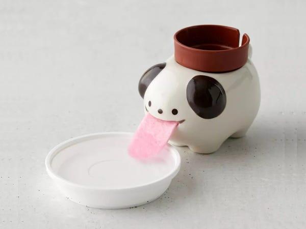 a white cat planter with a felt tongue in an attached bowl of water