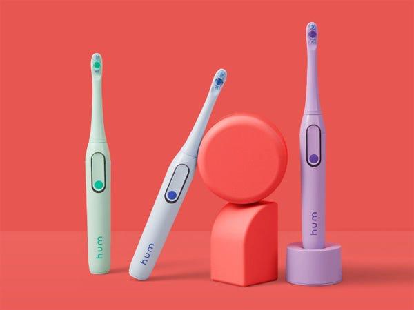 Three Hum Electric Toothbrushes on a red background