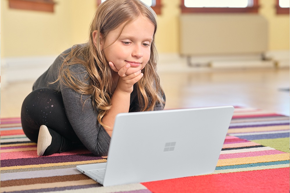 A child uses Surface Laptop SE at a desk in a classroom.
